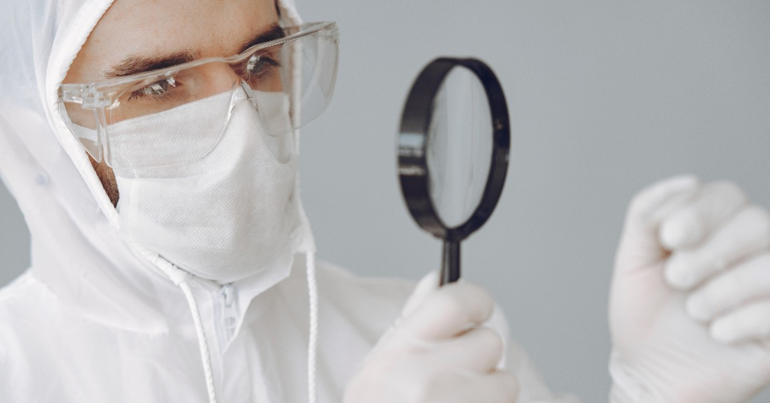 A cleanroom operator is using a magnifier to look at something.