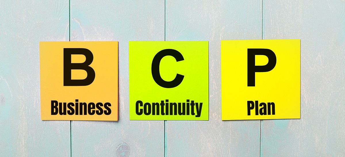 Three colored stickers with the text bcp business continuity plan a light blue wooden background